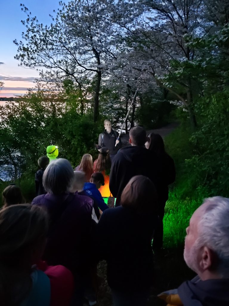 A scientist leads a group of people of all ages during an outreach event about bats.