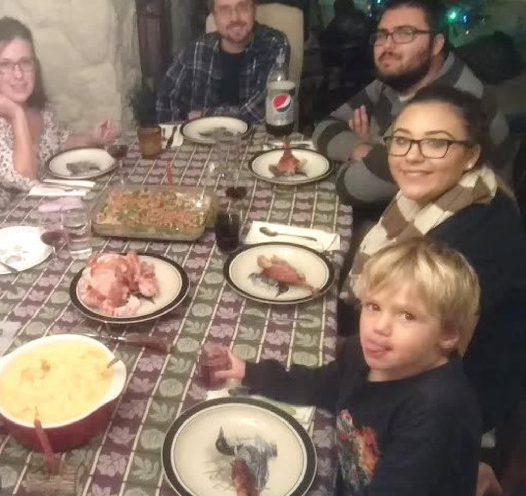 A group of people seated at a dining room table about to partake in a Thanksgiving dinner.
