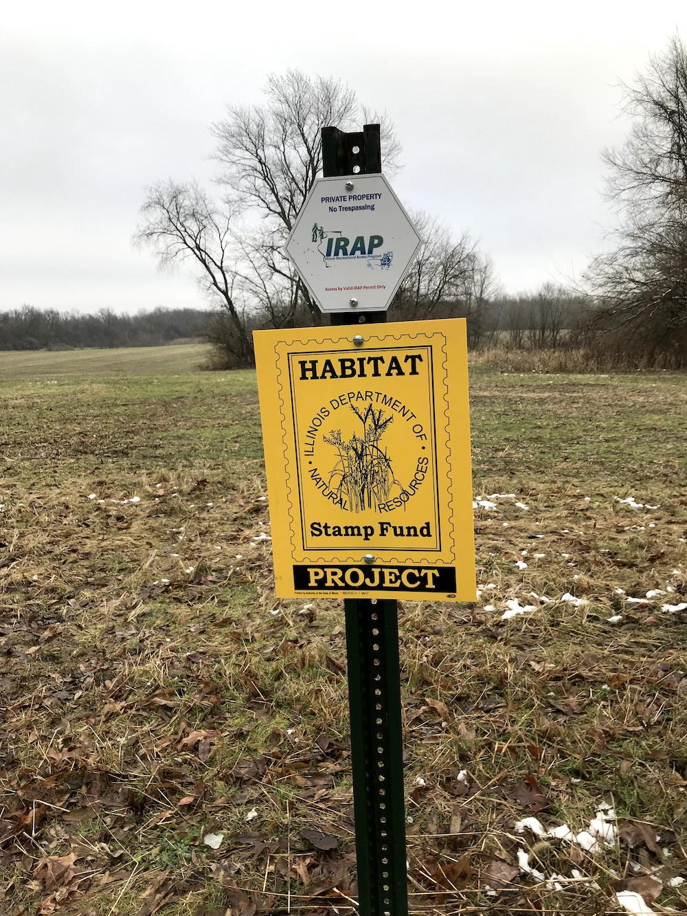 A sign in front of an agricultural field during the winter indicating the that the funding for habitat management was from the Habitat Stamp Fund Project and the Illinois Recreational Access Program.